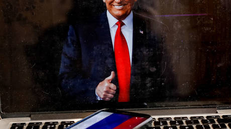 The US president Donald Trump portrait is shown on a computer screen against a Russian Federation flag displayed on a mobile phone screen